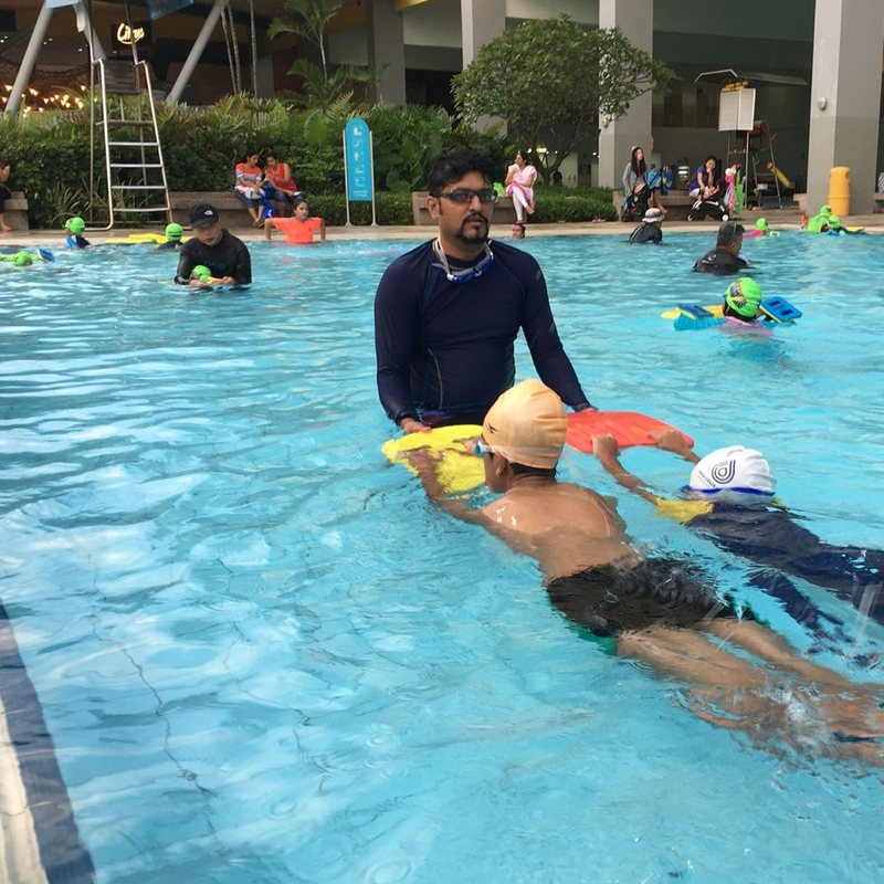 Coach Umesh “U.K.” Singh teaching a young swimmer