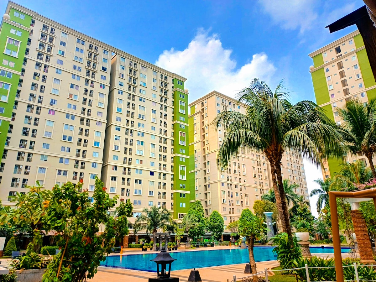 a swimming pool surrounded by palm trees in front of a multi - story building